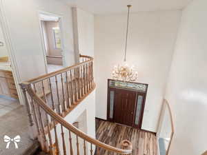 Foyer with hardwood / wood-style floors, a towering ceiling, and a chandelier