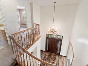 Foyer entrance featuring hardwood / wood-style flooring, a notable chandelier, and a high ceiling