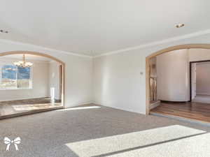 Empty room with crown molding, a notable chandelier, and hardwood / wood-style flooring