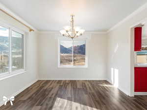 Unfurnished dining area with a notable chandelier, dark hardwood / wood-style floors, and ornamental molding