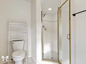 Bathroom featuring tile patterned floors, toilet, and walk in shower