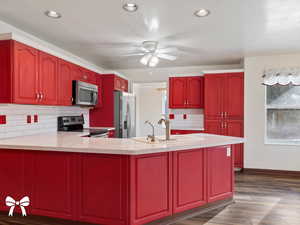 Kitchen featuring dark wood-type flooring, sink, ceiling fan, tasteful backsplash, and stainless steel appliances