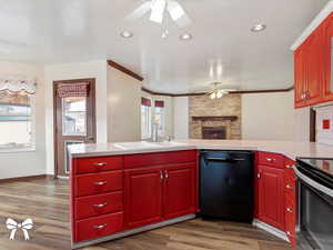 Kitchen with a brick fireplace, sink, black appliances, and wood-type flooring