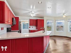 Kitchen with decorative backsplash, a textured ceiling, stainless steel appliances, dark wood-type flooring, and sink