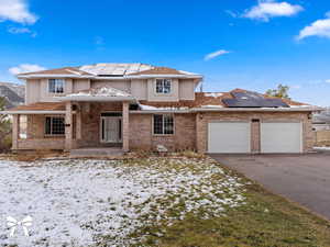 Front of property with solar panels, a porch, and a garage