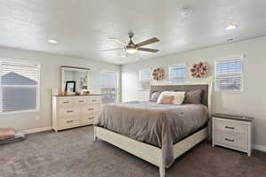 Carpeted bedroom with multiple windows, a textured ceiling, and ceiling fan