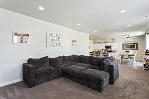 Living room with ceiling fan and dark carpet