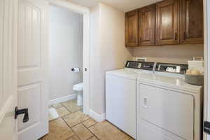 Clothes washing area featuring cabinets and washing machine and clothes dryer