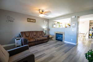 Living room with ceiling fan, wood-type flooring, and a tile fireplace