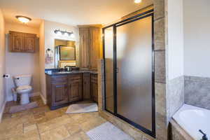 Full bathroom featuring vanity, separate shower and tub, and toilet