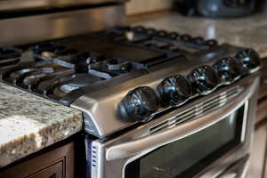 Details with gas stove and light stone countertops