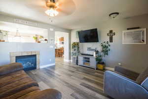 Living room featuring a fireplace, ceiling fan, and hardwood / wood-style floors