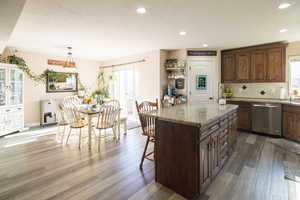 Kitchen featuring a kitchen island, stainless steel dishwasher, hanging light fixtures, and a healthy amount of sunlight