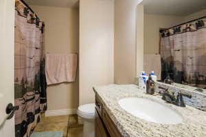 Bathroom with vanity, a shower with shower curtain, and toilet