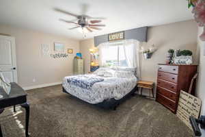 Bedroom featuring ceiling fan and dark colored carpet