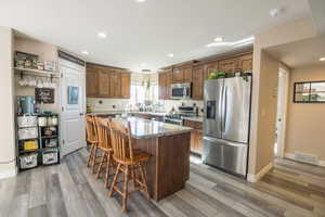 Kitchen featuring light stone countertops, light hardwood / wood-style flooring, a breakfast bar, a kitchen island, and appliances with stainless steel finishes