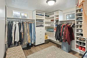 Walk in closet with dark wood-type flooring