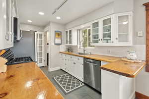 Kitchen featuring white cabinets, sink, stainless steel appliances, and wooden counters