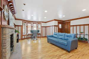 Living room featuring light hardwood / wood-style floors, a stone fireplace, and ornamental molding