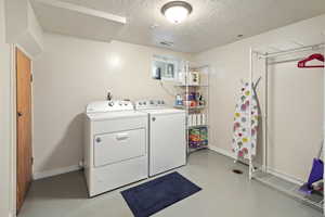 Laundry area with a textured ceiling and washer and clothes dryer