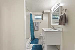 Bathroom featuring curtained shower, vanity, a textured ceiling, and toilet