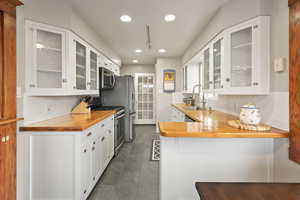 Kitchen featuring wood counters, stainless steel appliances, white cabinets, and sink