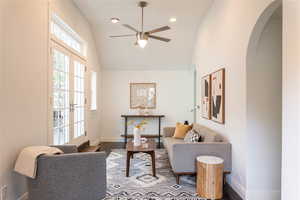 Family room featuring french doors, heated cement flooring, vaulted ceiling, and ceiling fan.