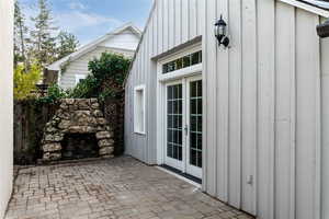 View of private fenced patio terrace with french doors and fireplace.