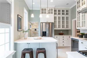 Kitchen featuring a kitchen breakfast bar, white cabinets, ornamental molding, and appliances with stainless steel finishes