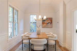 Dining area featuring original wainscoting, plenty of natural light, oak hardwood floors, and an inviting chandelier.