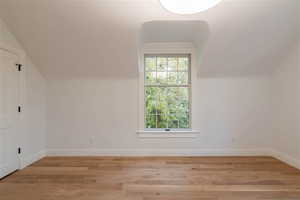 Additional bedroom with large window,  hardwood  flooring, lofted ceiling.