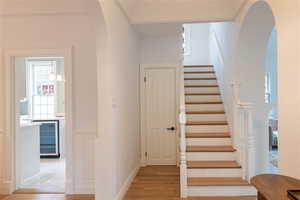 Stairs with hardwood flooring to upper level and coat closet.