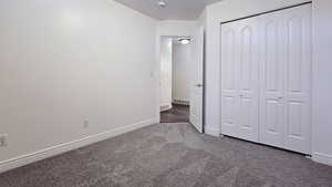 Unfurnished bedroom featuring dark colored carpet and a closet