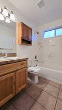 Full bathroom with toilet, vanity, tile patterned floors, and tiled shower / bath