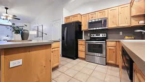 Kitchen featuring vaulted ceiling, ceiling fan, sink, black appliances, and light tile patterned flooring