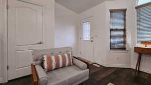 Sitting room with lofted ceiling and dark wood-type flooring