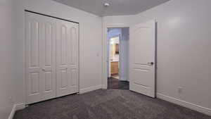 Unfurnished bedroom featuring a closet and dark carpet