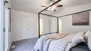 Bedroom with dark colored carpet, ceiling fan, and lofted ceiling