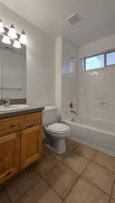 Full bathroom with toilet, vanity, tile patterned floors, and tiled shower / bath