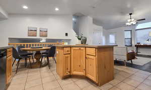 Kitchen with a center island, vaulted ceiling, ceiling fan, and light tile patterned flooring