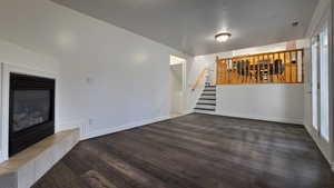 Unfurnished living room featuring a fireplace, dark wood-type flooring, and a textured ceiling