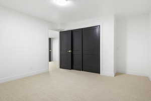 Unfurnished bedroom featuring light carpet and a closet