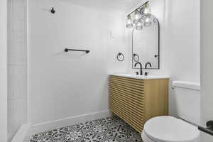 Bathroom featuring tile patterned floors, vanity, a textured ceiling, and toilet