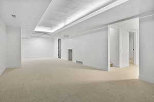 Empty room featuring light colored carpet and a textured ceiling