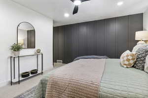 Bedroom with light carpet, a textured ceiling, and ceiling fan