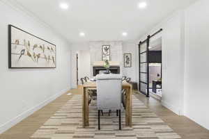 Dining area featuring light wood-type flooring, a barn door, and ornamental molding