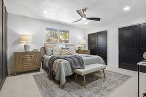 Bedroom featuring a textured ceiling, ceiling fan, and light carpet