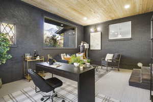 Carpeted home office featuring wooden ceiling and brick wall