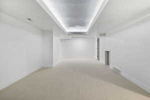 Corridor featuring light colored carpet and a textured ceiling