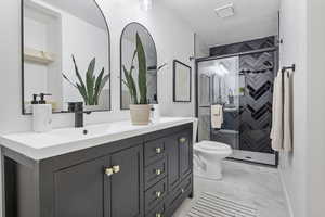 Bathroom with a textured ceiling, vanity, toilet, and walk in shower